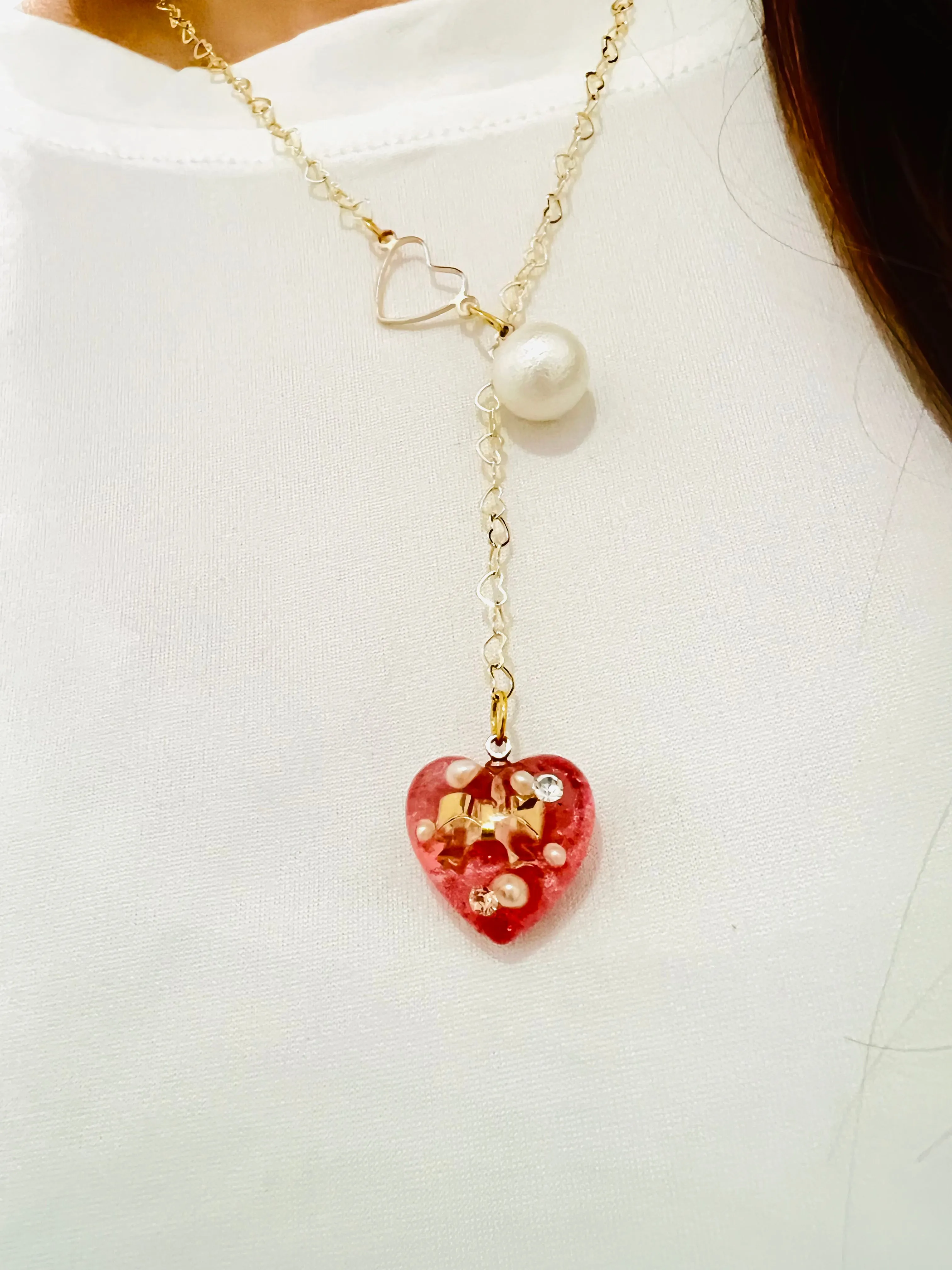 Heart-shaped gold necklace with hanging red heart